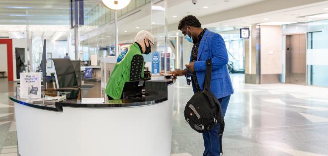 A man stands next to an information booth speaking to a volunteer