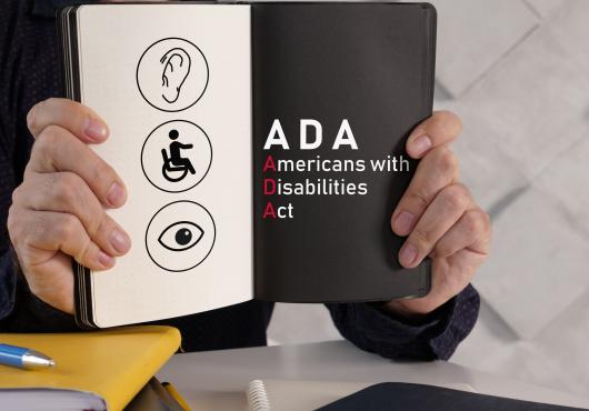 A person holds a book open to a page that reads "ADA"